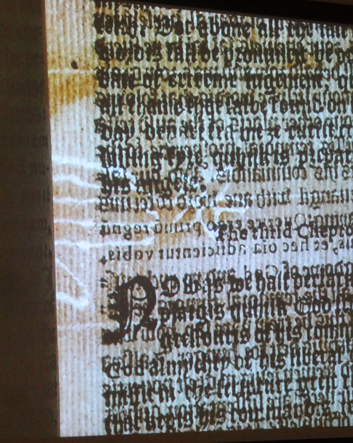 A projection of a hand-and-star watermark peeking out of the gutter from a 1566 London imprint