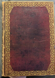 Image of the red cover of a book with gold tooled edges