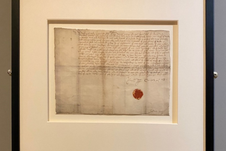 Photo of an archival leaf in a frame on the wall.